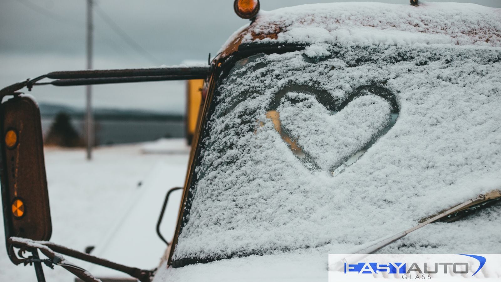 A hear written in snow on the windshield of a truck. Show your windshield some love by repairing or replacing it as soon as possible